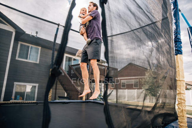 Papa rebondissant sur le trampoline avec tout-petit fils — Photo de stock