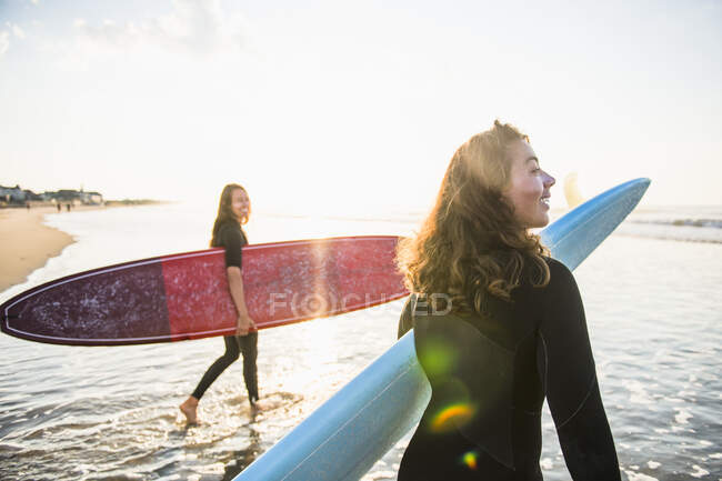 Duas mulheres amigas indo para um nascer do sol surfe de verão — Fotografia de Stock