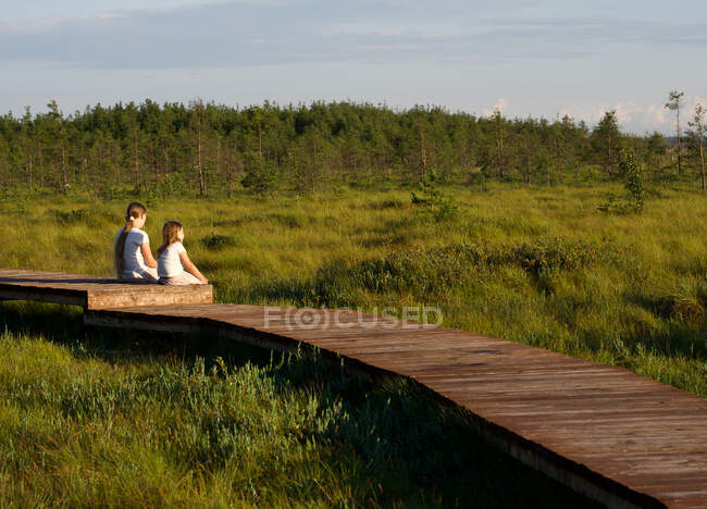 Children sitting on Boardwalk looking at Nature reserve Landscape — Stock Photo