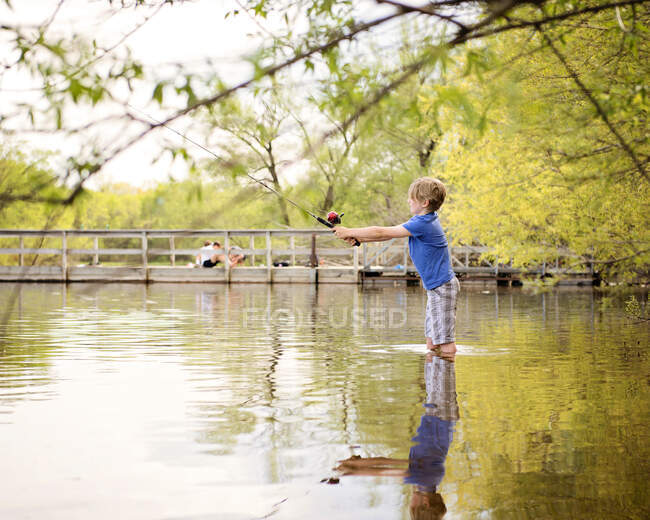 Jovem loiro menino pesca por lago Shore — Fotografia de Stock
