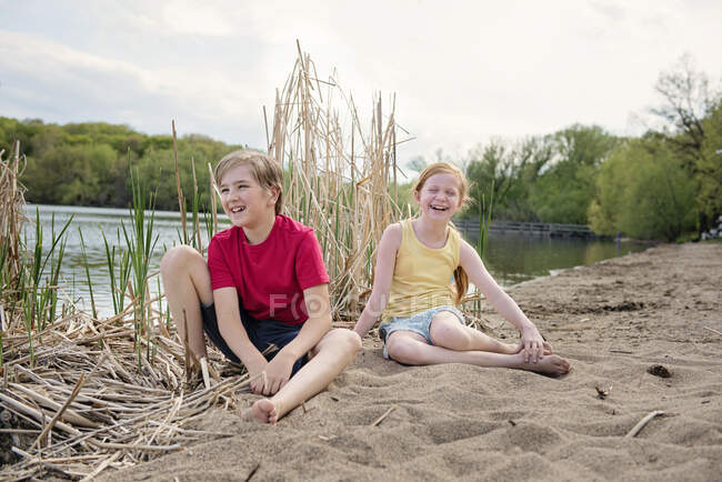 Jeune garçon et fille jouant dans le sable près d'un lac — Photo de stock