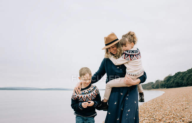 Mamá y sus hijos disfrutando de un paseo juntos por la playa en Inglaterra - foto de stock