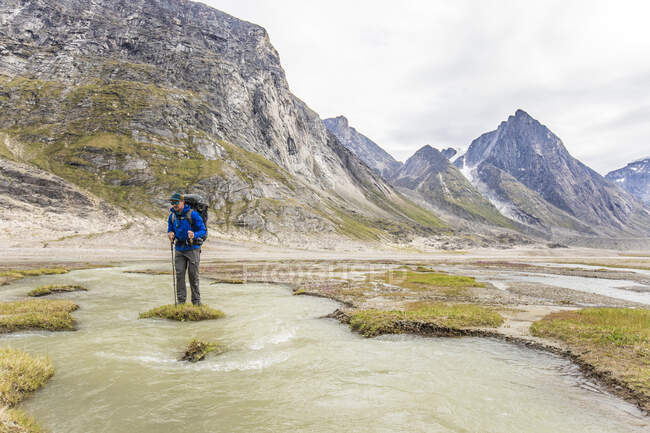 Backpacker steht auf einer grasbewachsenen Insel inmitten eines Flusskanals — Stockfoto
