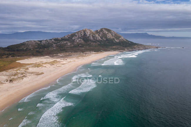 Un hermoso paisaje de un acantilado de una playa con rocas en el horizonte - foto de stock