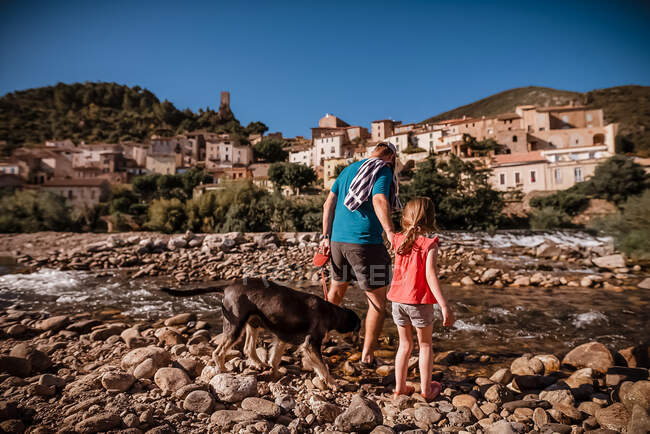 Батько, дочка і собака прибувають до річки на півдні Франції. — стокове фото