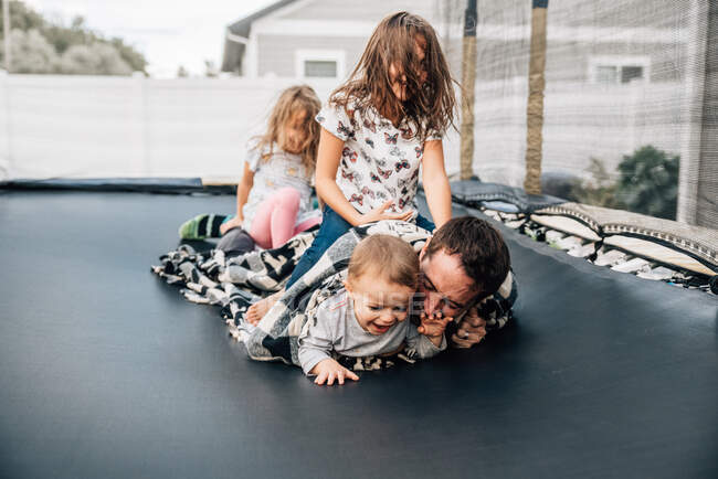 Family jumping on a trampoline in the backyard — Stock Photo