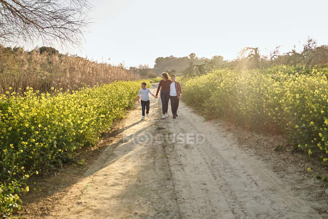 Madre camina a lo largo de un sendero mientras habla con sus hijos - foto de stock