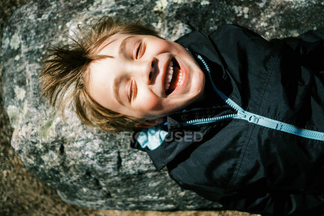 Criança deitada na rocha e desfrutando dos primeiros raios de sol quentes no rosto — Fotografia de Stock