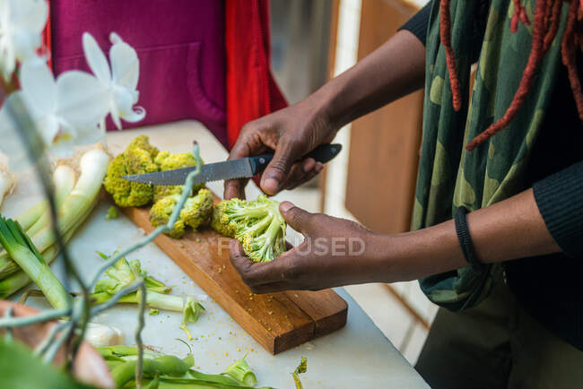 Mulher negra cortando brócolis, na cozinha — Fotografia de Stock