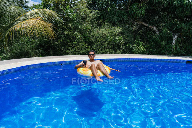 Uomo avendo divertente con un ciambella in il piscina — Foto stock
