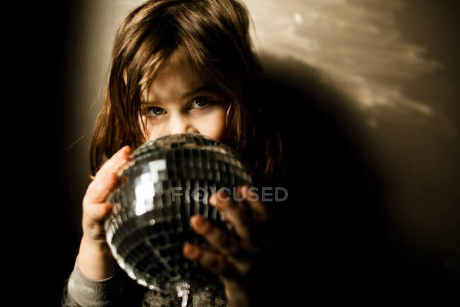 Young girl wearing a leopard pajamas holding a disco ball — Stock Photo