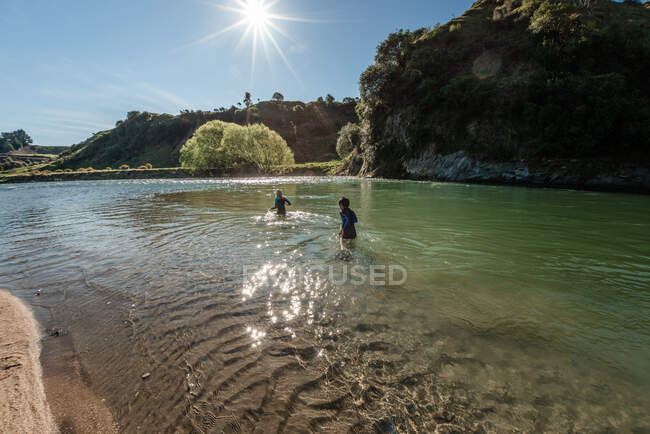 Bambini preadolescenti che camminano nel fiume Nuova Zelanda in una giornata di sole — Foto stock
