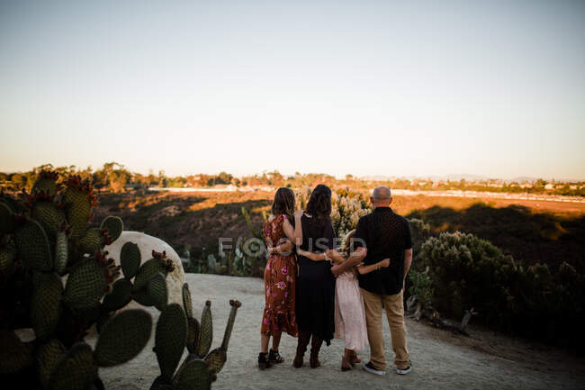 Портрет семьи, обнимающей друг друга на закате в саду — стоковое фото