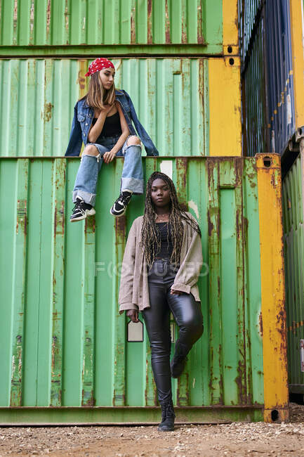 Zwei multiethnische Frauen posieren umgeben von Schiffscontainern — Stockfoto