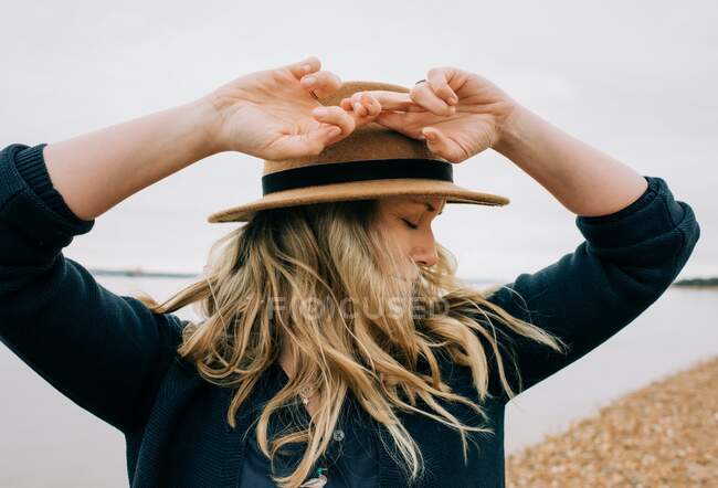 Woman stood at the beach with her hair blowing in the wind in England — Stock Photo