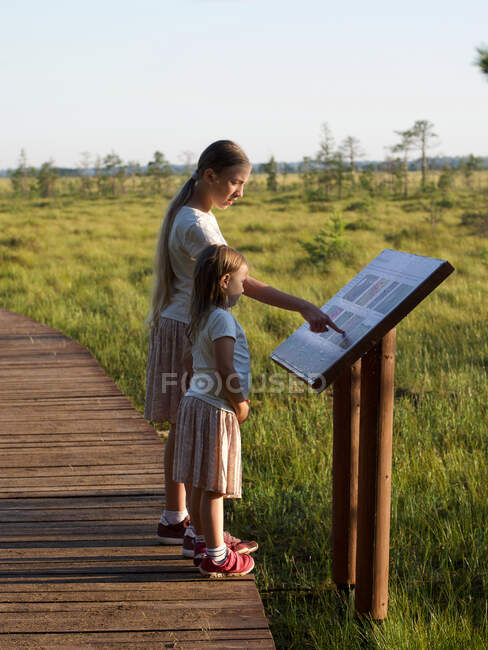 Kinder stehen im Naturschutzgebiet und schauen auf Infotafel — Stockfoto