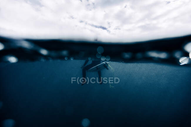 Niño surfista tranquilo sentado en la parte superior de la tabla, bajo el agua, ola - foto de stock