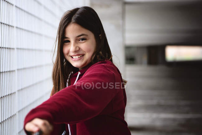 Hermosa chica adolescente sonriente con pelo largo y oscuro en el garaje de estacionamiento. - foto de stock