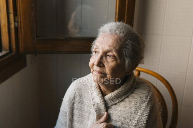 Портрет пожилой женщины, смотрящей в окно — стоковое фото