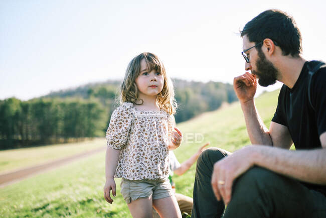 Маленька дівчинка дивиться на відстань, стоячи поруч зі своєю сім'єю на пагорбі — стокове фото