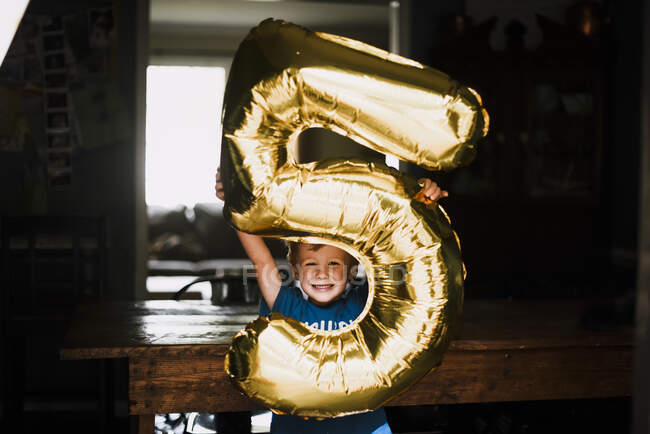 Ragazzo giovane con grande foglio d'oro numero cinque palloncino il quinto compleanno — Foto stock