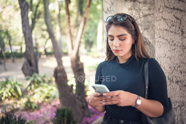 Женщина в парке с помощью мобильного телефона — стоковое фото