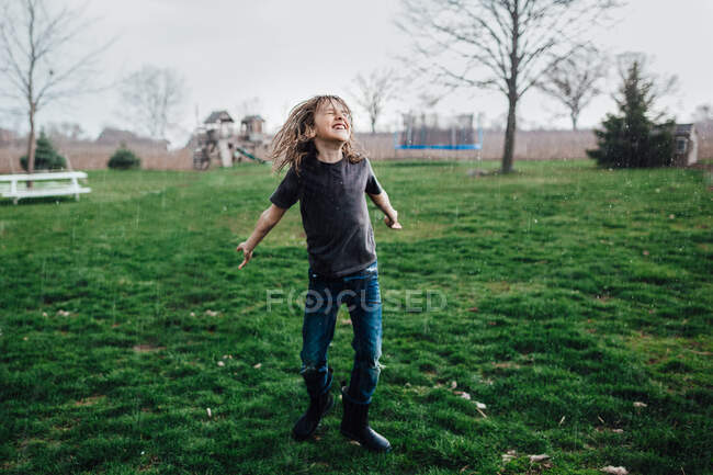 Маленький хлопчик сміється і танцює під дощем — стокове фото