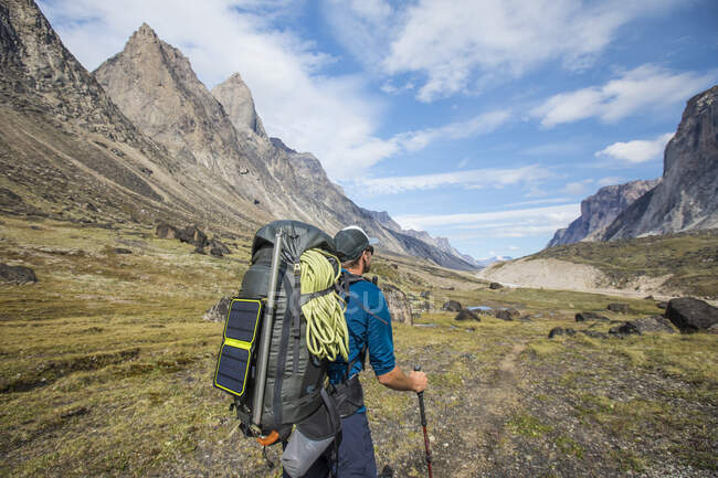 Backpacker hiking with solar panel attached to backpack. — Stock Photo
