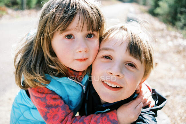 Dos niños pequeños abrazándose y sonriendo en una caminata al aire libre en Nueva Inglaterra - foto de stock
