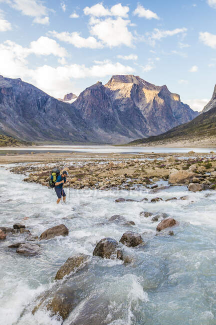 Sac à dos traverse soigneusement une rivière sur l'île de Baffin, Canada. — Photo de stock