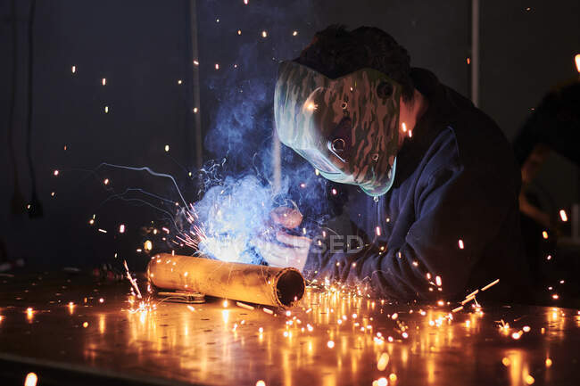 Mechanic in protective helmet welding pieces — Stock Photo