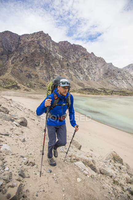 Backpacker indossa giacca pioggia escursioni su terreni rocciosi. — Foto stock