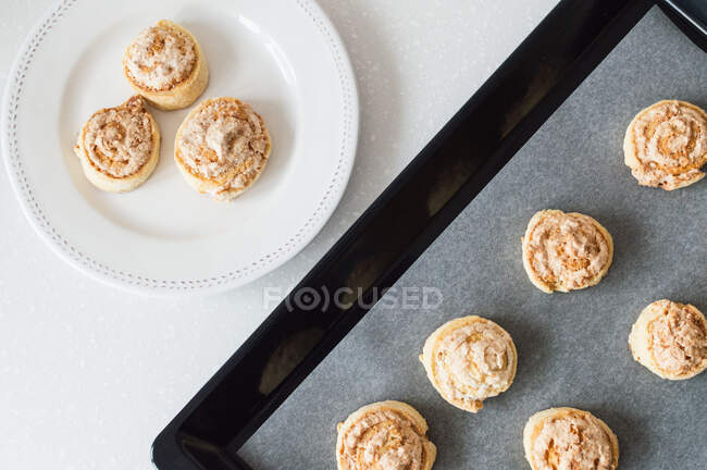 Kekse auf weißem Teller und schwarzes Backblech auf weißer Arbeitsplatte — Stockfoto