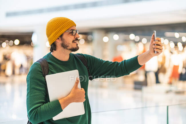 Homem espanhol falando em videochamada com smartphone no shopping — Fotografia de Stock