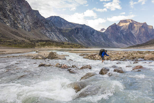 Backpacker attraversa freddo, fiume che scorre veloce sull'isola di Baffin — Foto stock