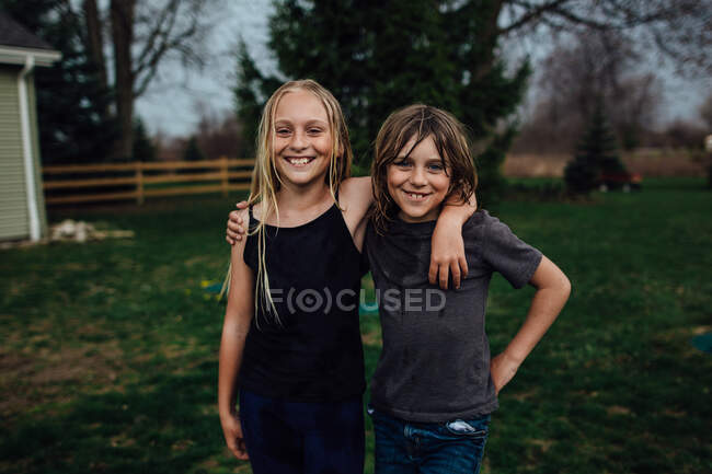 Мальчик и девочка с большими улыбками позируют перед камерой — стоковое фото