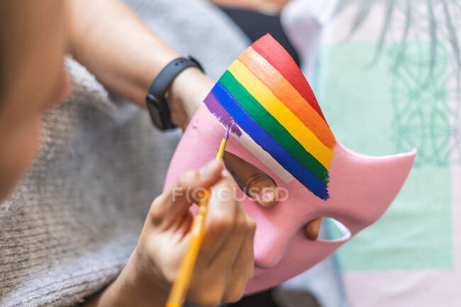 Painter giving purple brushstroke on pink painted mask for pride day — Stock Photo