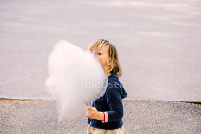 Cute young girl 3-4 years old eating cotton candy — Stock Photo