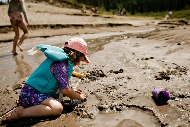 Giovane ragazza che gioca in spiaggia facendo un castello di sabbia in estate — Foto stock