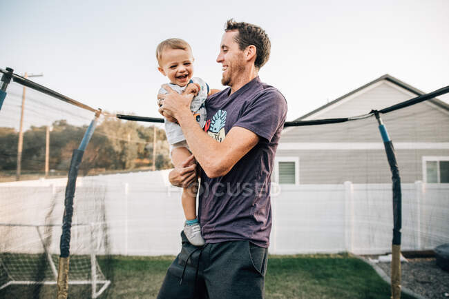 Dad laughing on trampoline with toddler son — Stock Photo