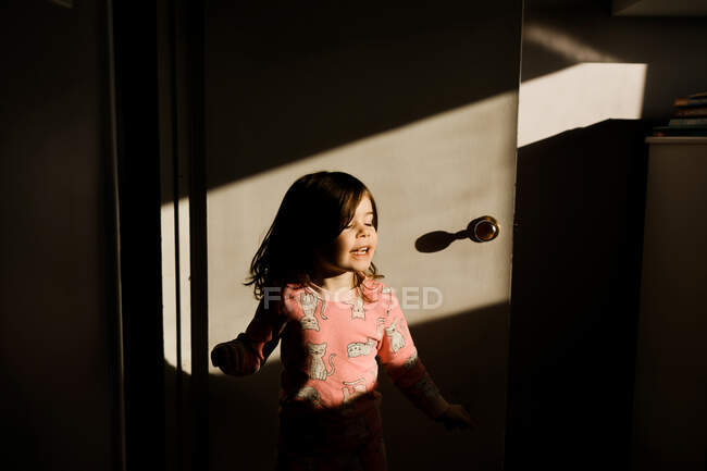 Young girl twirling in front of bedroom door in the sunlight — Stock Photo