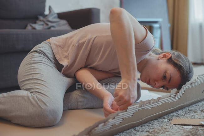 Attraktive Hausfrau mit Schraubenzieher baut Möbel selbst zusammen. Frauenpower. Haushalt und Wohnungseinrichtung. — Stockfoto
