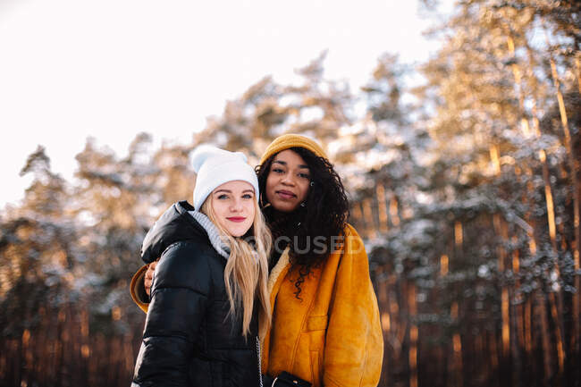 Retrato de duas jovens mulheres em pé contra árvores durante o inverno — Fotografia de Stock