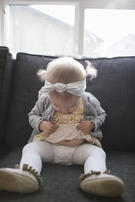 Toddler girl, lifting dress looking at diaper, stomach. — Stock Photo