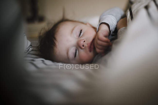 Brun chevelu sommeil bébé garçon paisiblement co-sommeil — Photo de stock