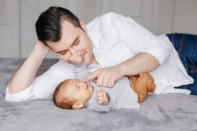 Father's day holiday. Happy proud dad playing with newborn baby boy. — Stock Photo