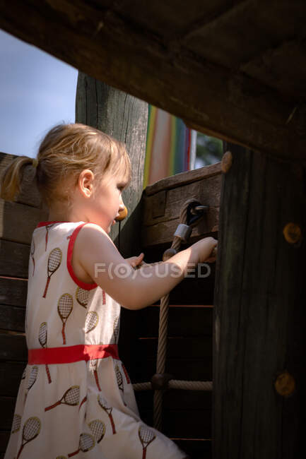 Chica joven arrastrándose por la red en el patio de recreo - foto de stock
