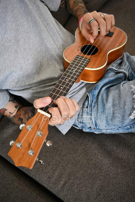 Un joven toca un ukelele de madera - foto de stock