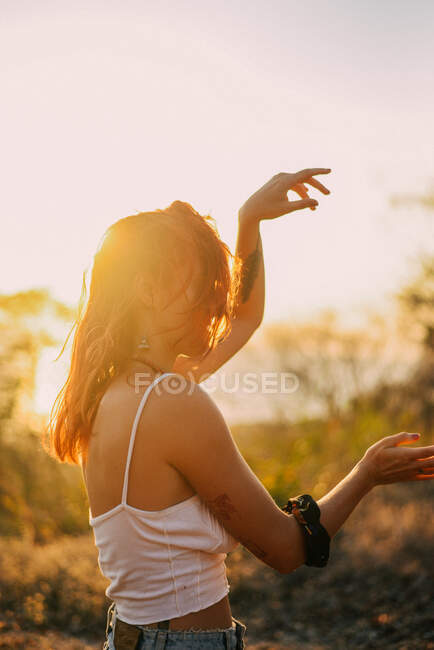 Подсвеченный портрет счастливой женщины, танцующей на закате — стоковое фото