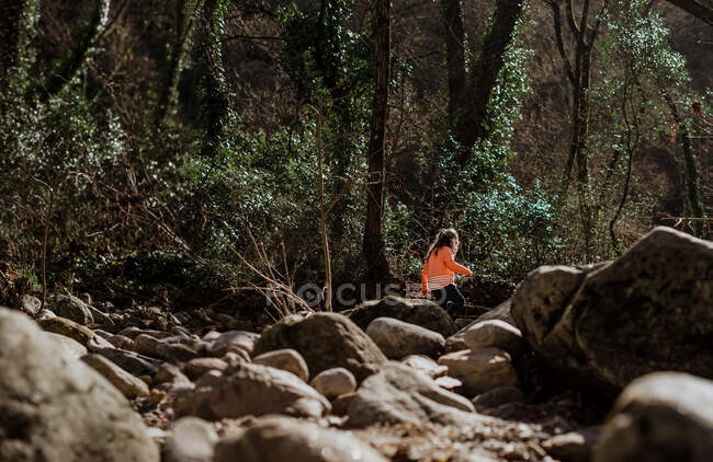 Mädchen läuft durch riesige Felsen im Wald auf dem Land — Stockfoto